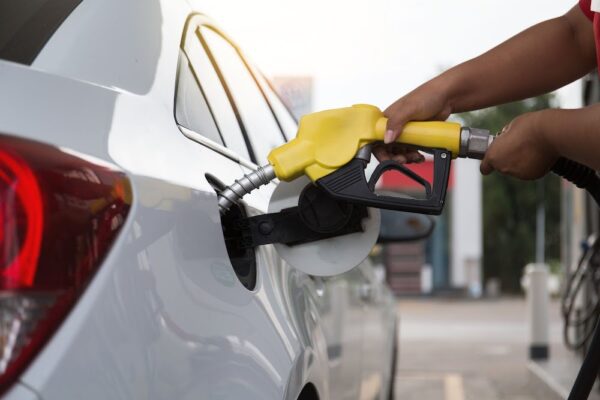 a person holding a gas nozzle to a car