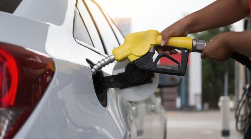 a person holding a gas nozzle to a car